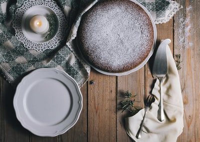 在白色陶瓷盘上放馅饼，旁边是白色的茶点蜡烛和蛋糕服务器